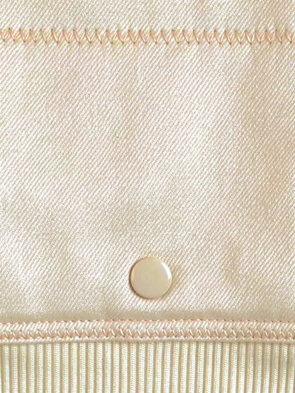 Close up of the smooth twill weave of the cropped bomber jacket, with a flat cream press stud and the ribbed hem band