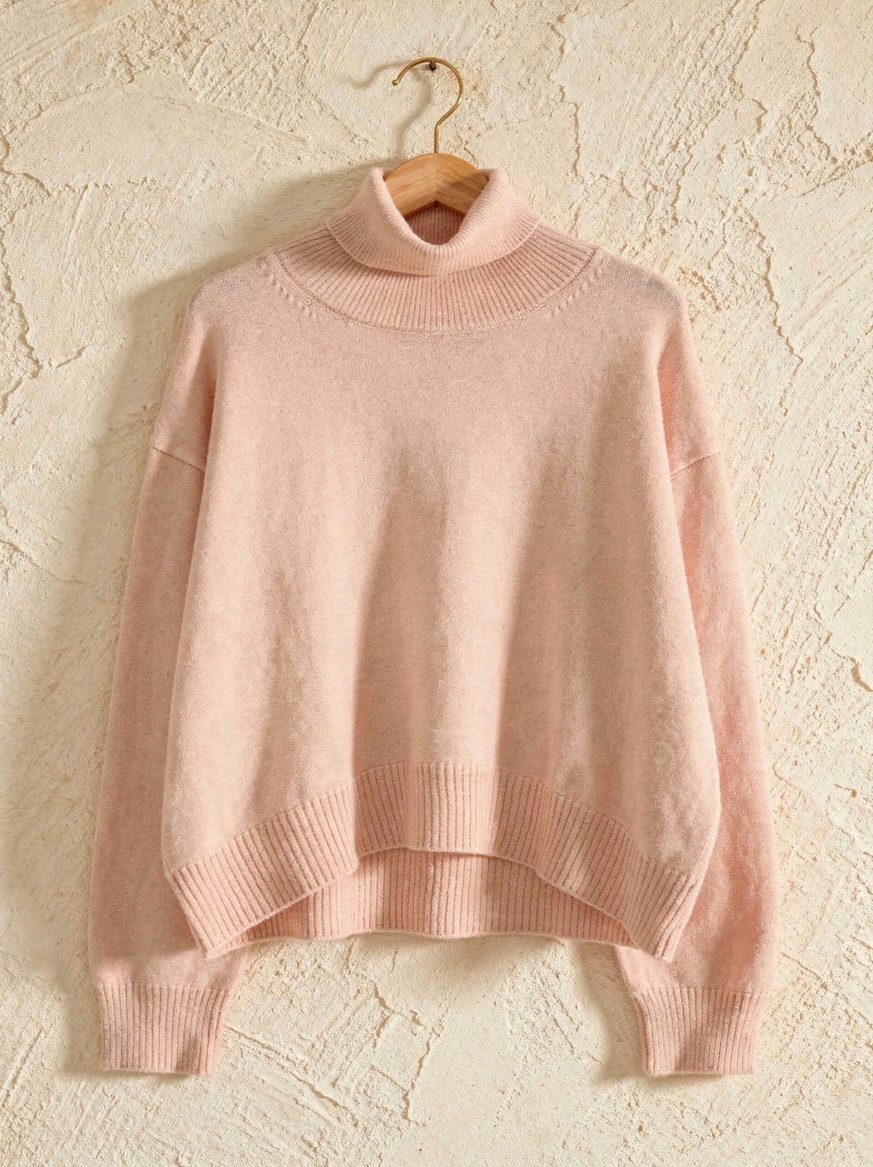 Blush pink cropped turtleneck jumper on a wooden hanger