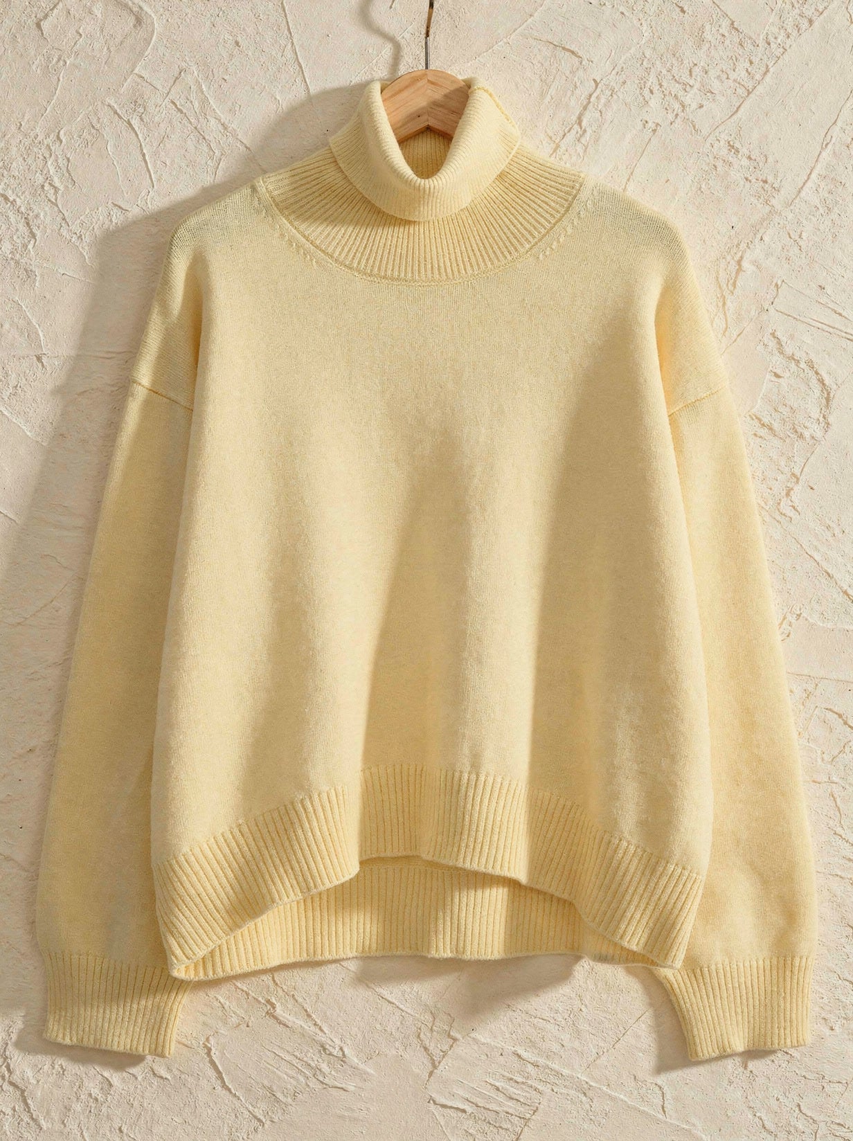 Butter yellow cropped turtleneck jumper on a wooden hanger