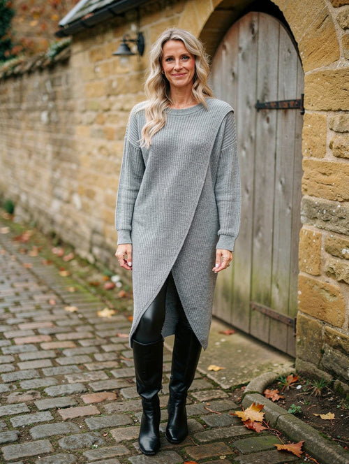 Woman wearing the grey marl crossover-hem rib-knit jumper dress with leather leggings and knee boots in a village lane