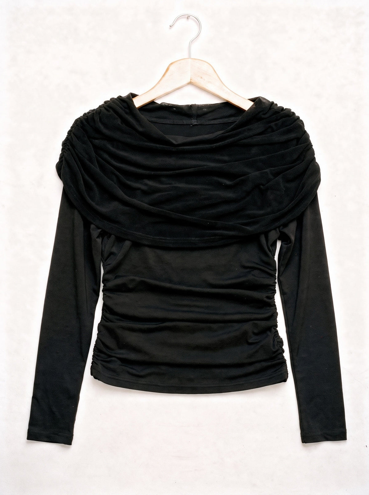 Black draped top on a hanger, showing the wide pleated shawl collar and the ruched body