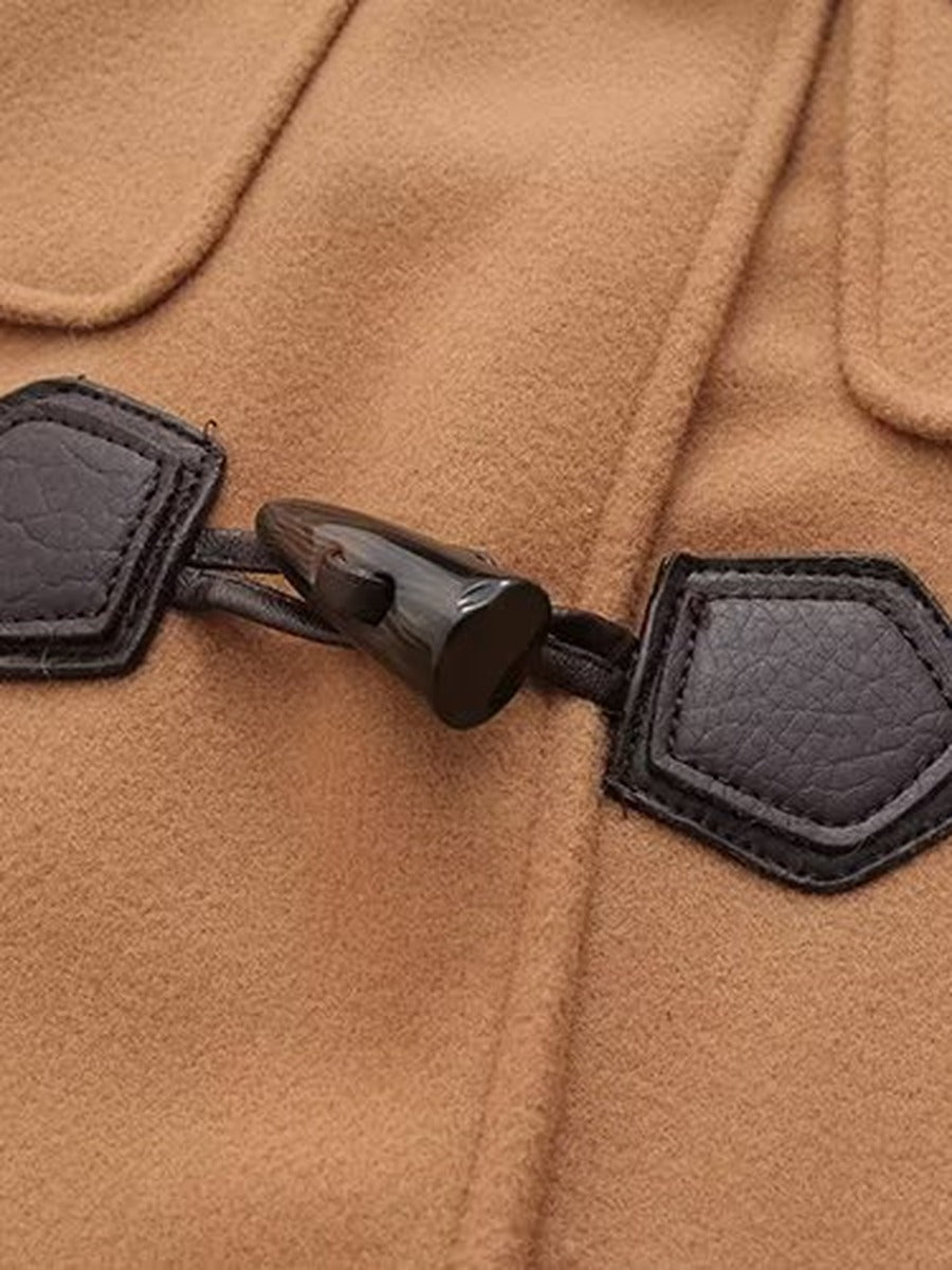 Horn style toggle on a leather look tab on a camel duffle coat