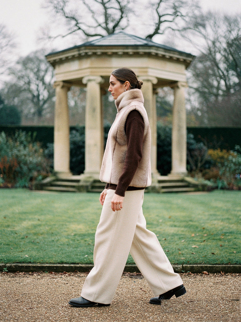 Faux fur gilet in Champagne worn over a roll neck jumper, side view