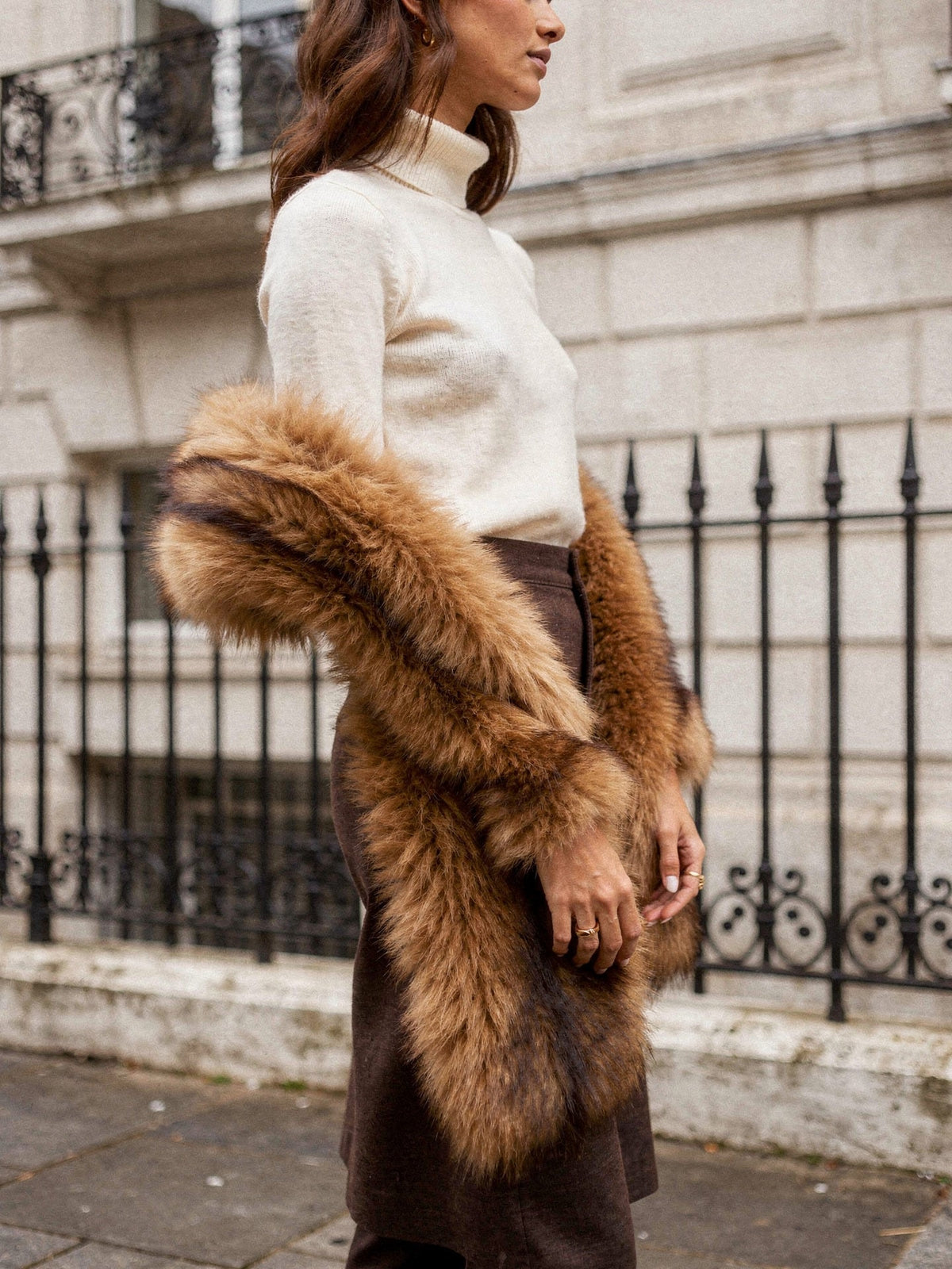 Faux fur scarf wrapped once at the neck over a cream roll neck on a Georgian street, both ends hanging to the hip