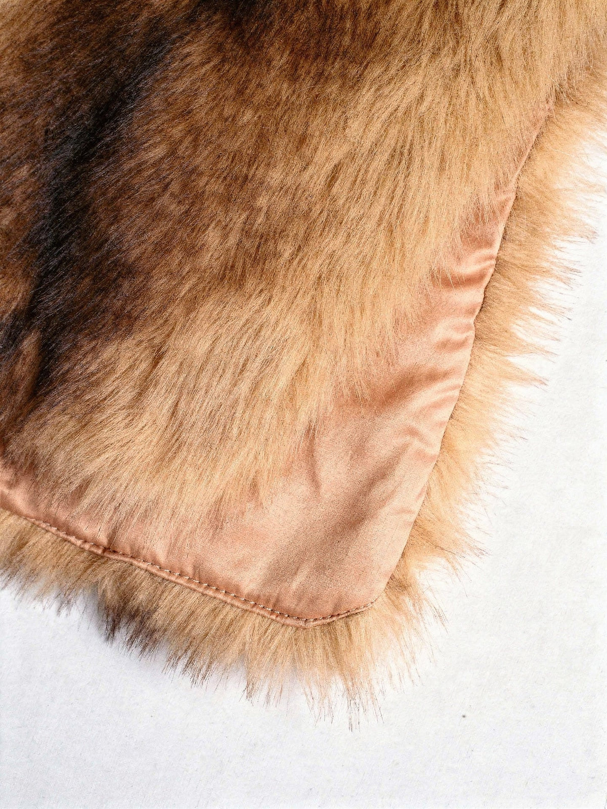 Close-up of the peach satin lining and the stitched bound edge of the faux fur scarf