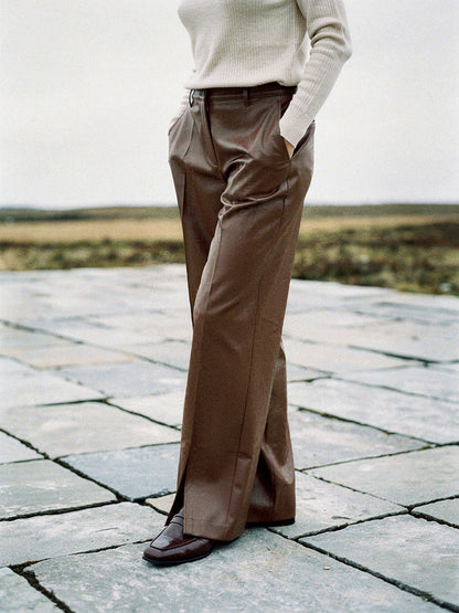 Womens chestnut faux leather trousers worn full length on a limestone pavement