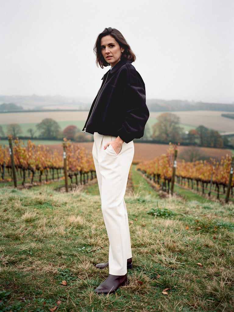 Black faux suede bomber jacket with batwing sleeves worn in a downland vineyard
