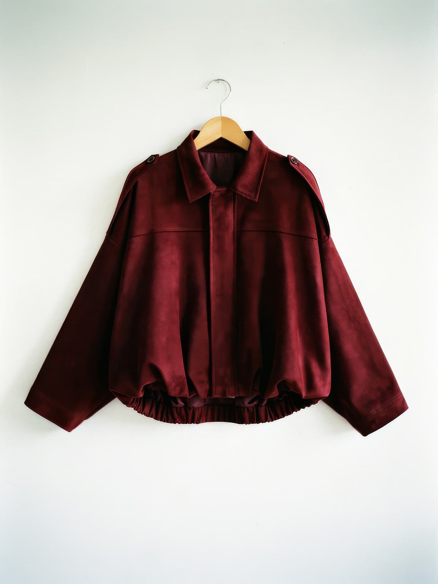 Burgundy cropped faux-suede jacket with batwing sleeves on a wooden hanger