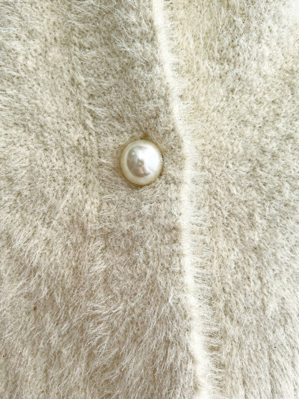 Close up of the long pile fluffy knit and one domed pearl button