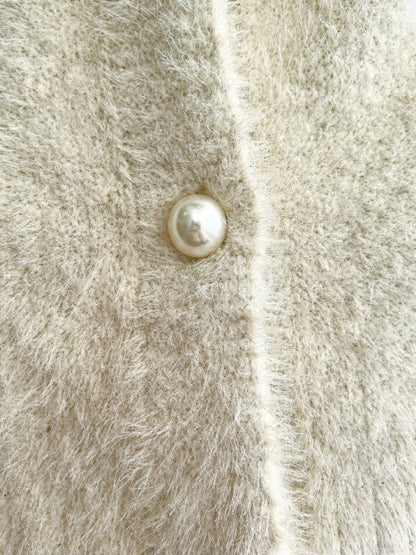 Close up of the long pile fluffy knit and one domed pearl button