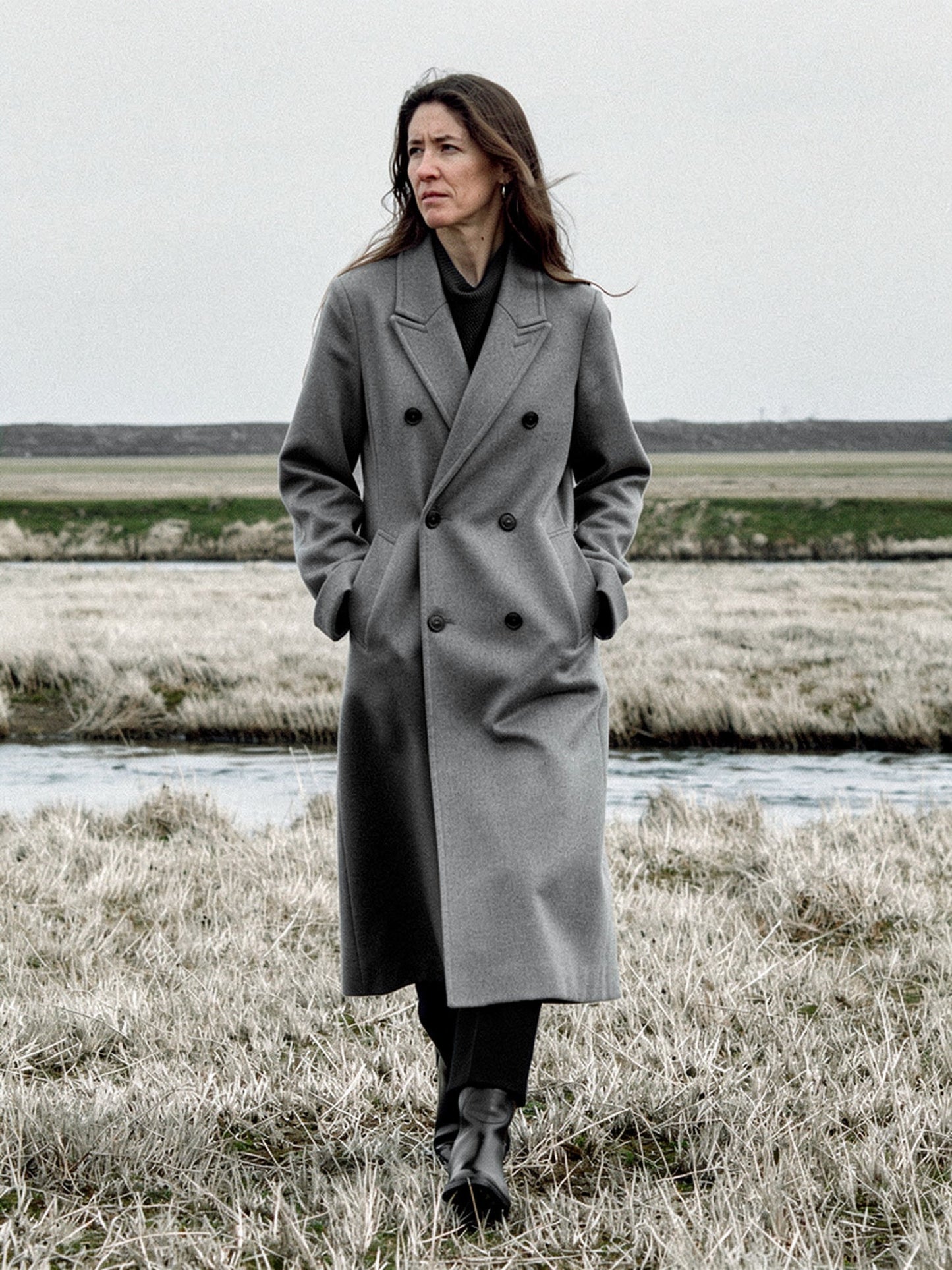 Grey wool coat worn open on a salt marsh, double breasted and oversized, falling to mid calf