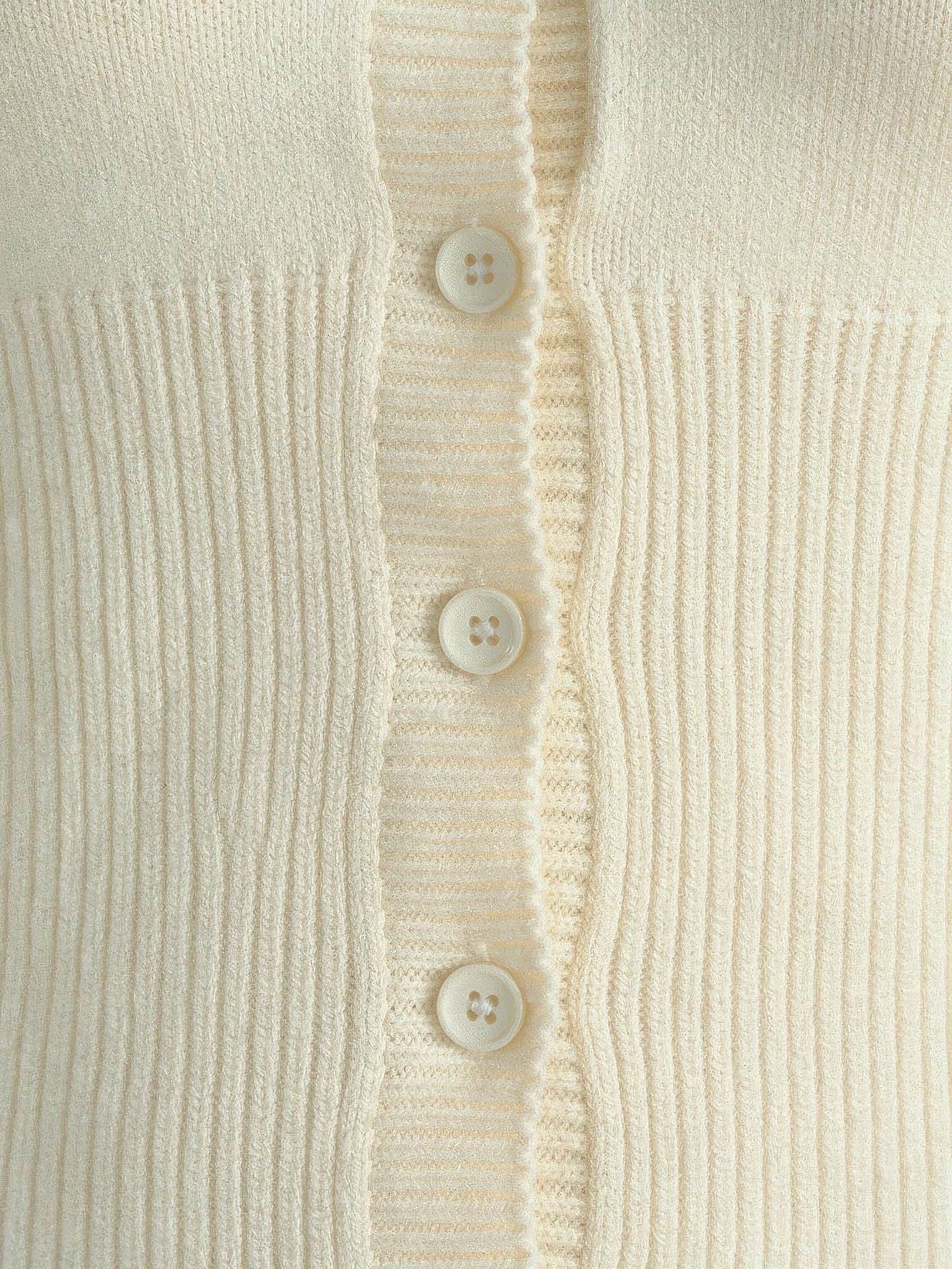 Close-up of the ribbed knit and scalloped button placket of the cropped cardigan