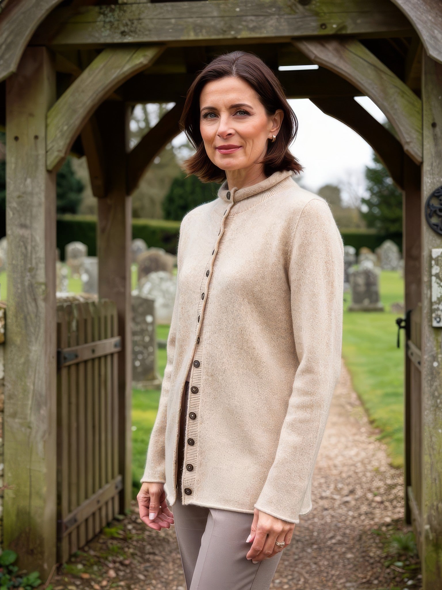 Sand mock-neck wool cardigan worn at a country churchyard gate