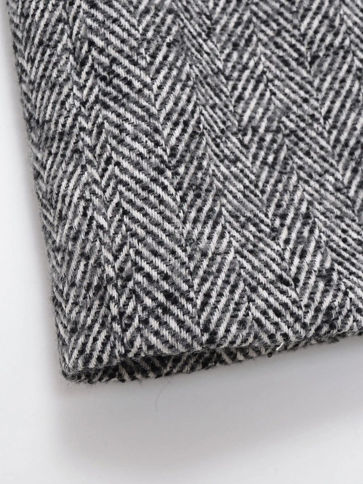 Close up of the woven black and off white herringbone cloth of the midi coat