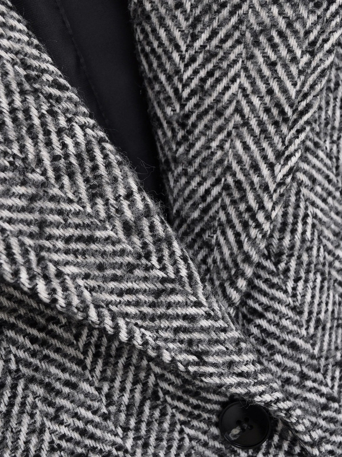 Wide notch lapel and black lining of the grey herringbone midi coat