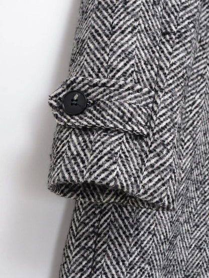 Buttoned tab on the sleeve cuff of the grey herringbone midi coat