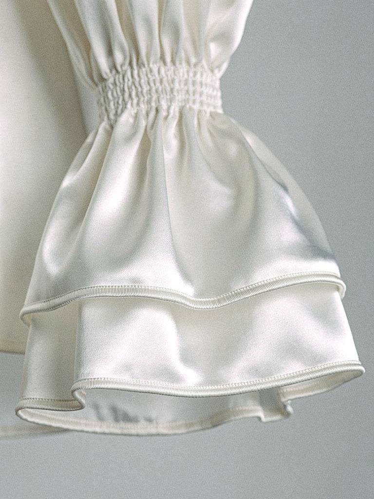 Close up of the shirred cuff band and double flounce on an ivory satin blouse