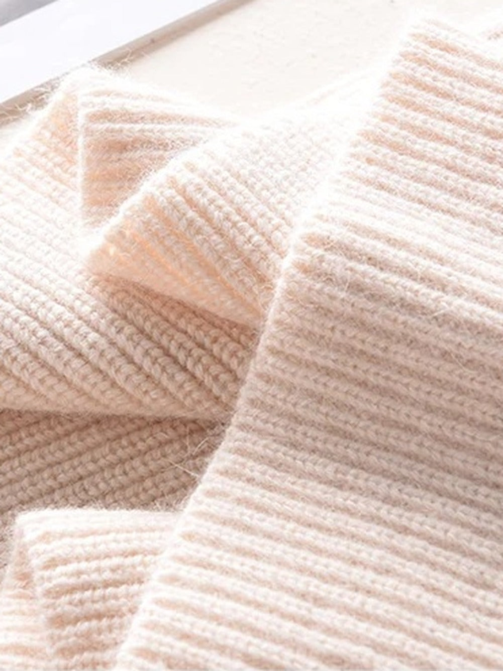 Knitted hood in Millet folded, showing the rib and the soft surface of the knit