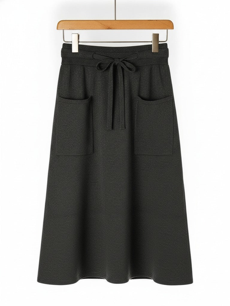 Knitted midi skirt in anthracite, a dark charcoal grey, hung flat to show the patch pockets and drawstring waist