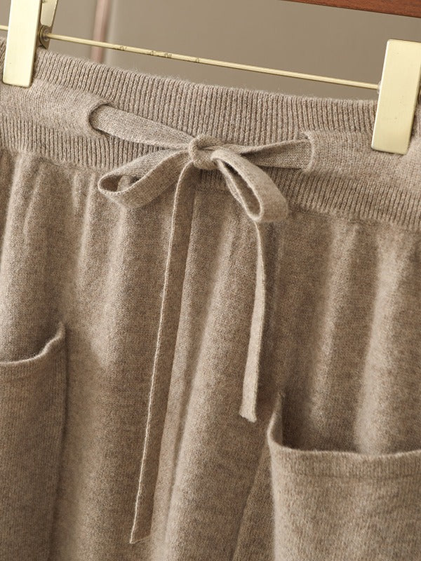 Close view of the ribbed elasticated waistband, the knitted drawstring tied in a bow and the folded top edge of both patch pockets