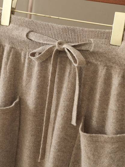 Close view of the ribbed elasticated waistband, the knitted drawstring tied in a bow and the folded top edge of both patch pockets