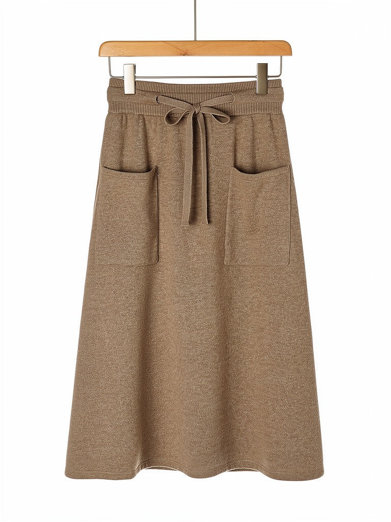 Knitted midi skirt in hazelnut, hung flat to show the A-line sweep, the ribbed drawstring waistband and the two patch pockets