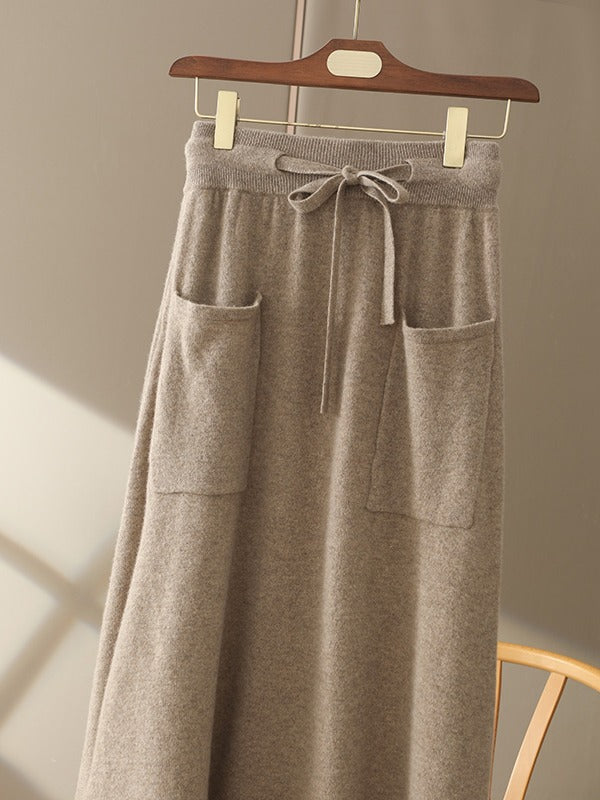 Supplier photograph of the knitted midi skirt in hazelnut on a wooden hanger, showing the brushed knit and the bow at the waist