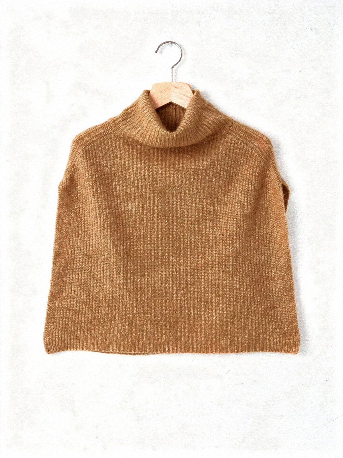 Knitted poncho in Bran on a hanger, showing the wide rib and the funnel neck collar