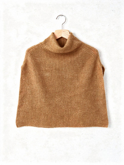 Knitted poncho in Bran on a hanger, showing the wide rib and the funnel neck collar