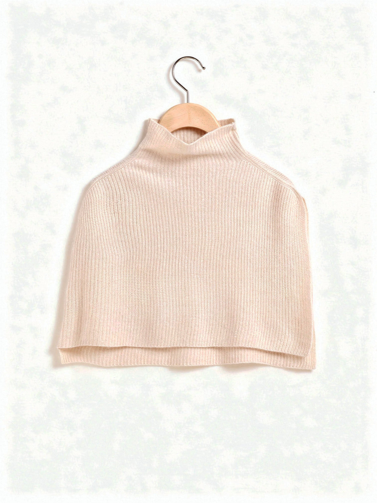 Knitted poncho in Wafer on a hanger, showing the wide rib and the funnel neck collar