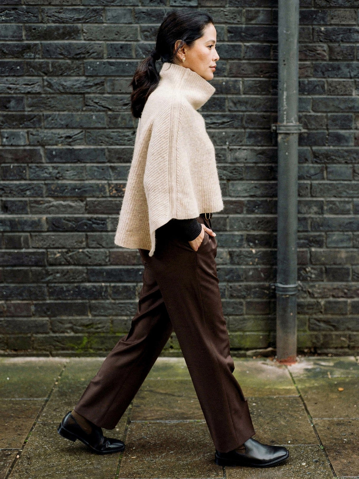 Knitted poncho in Wafer seen from the side, wide rib capelet with a funnel neck collar