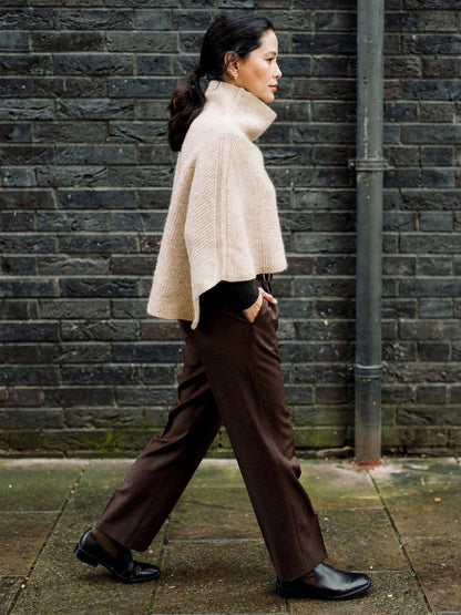 Knitted poncho in Wafer seen from the side, wide rib capelet with a funnel neck collar