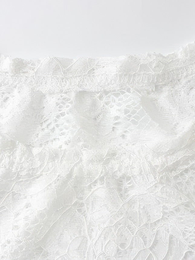 Detail of the high round neckline and the floral lace of the mini dress