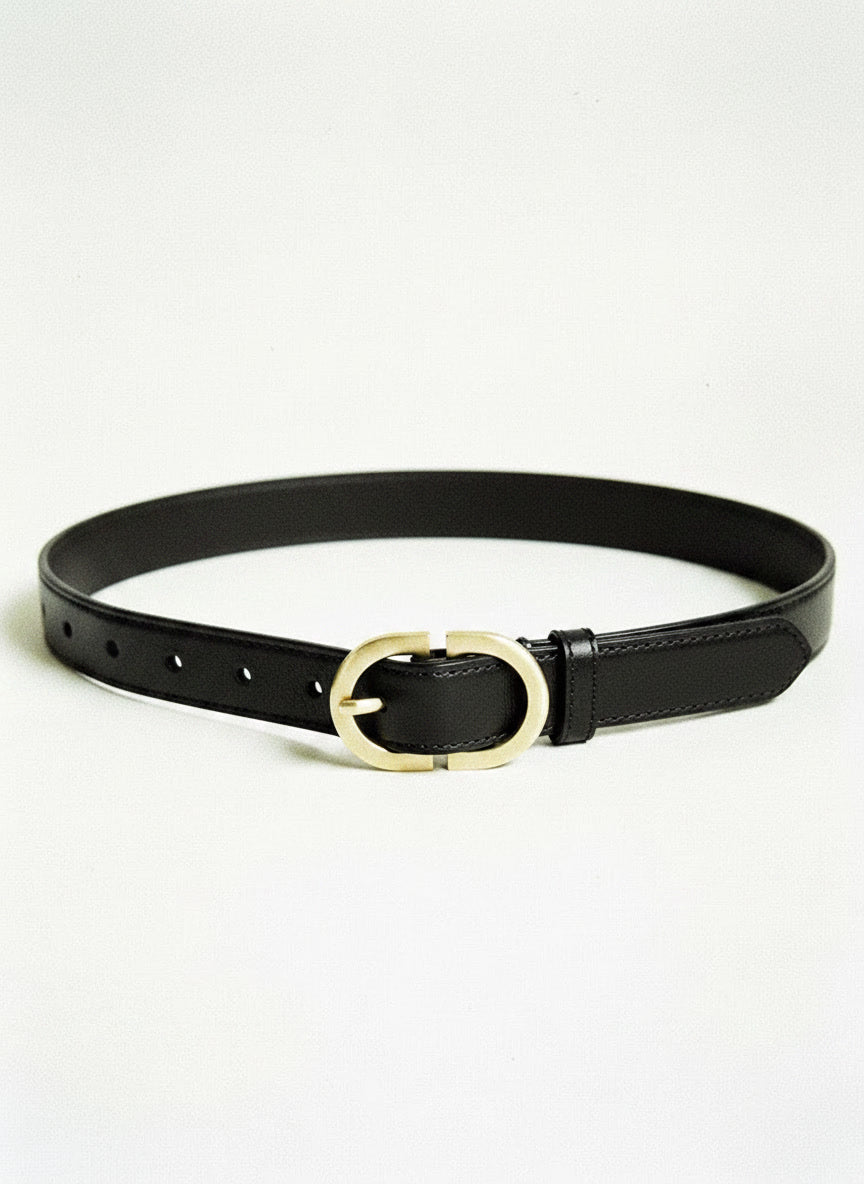 Slim leather belt in black with a brushed gold oval buckle, laid flat