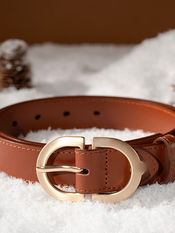 Leather belt in tan photographed on snow, showing the buckle and the punched holes