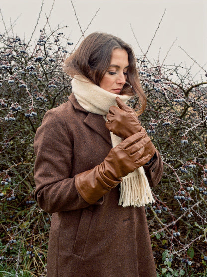 Leather gloves in Kestrel tan sheepskin worn by a frosted blackthorn hedge