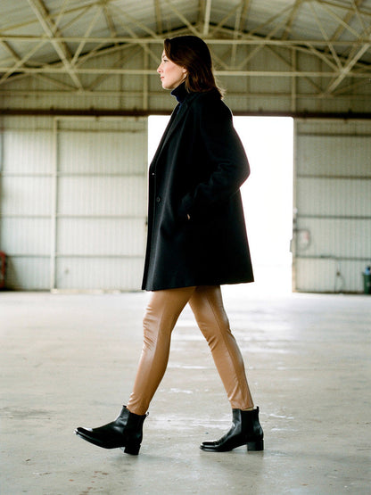Biscuit leather-look leggings worn with a black wool coat and flat boots