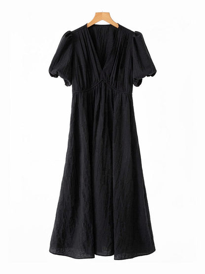 Long black dress on a hanger, showing the deep V neck, short puff sleeves and full gathered skirt