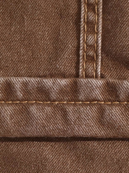 Close up of the stretch denim twill of the long jean skirt in tanbark brown, showing the diagonal weave, the turned hem and the tan topstitching