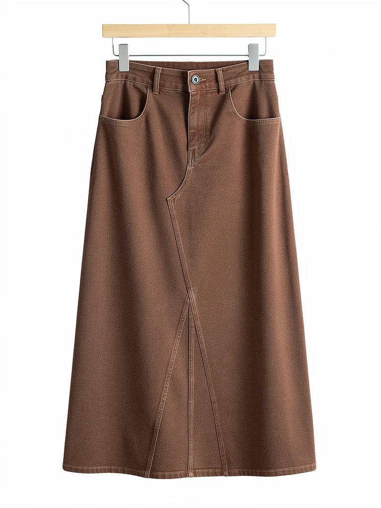 Long jean skirt in tanbark brown denim on a plain wooden hanger against white, showing the flat jean waistband, the zip fly, the two scoop pockets and the full A-line sweep