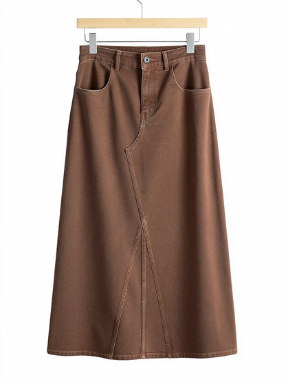 Long jean skirt in tanbark brown denim on a plain wooden hanger against white, showing the flat jean waistband, the zip fly, the two scoop pockets and the full A-line sweep