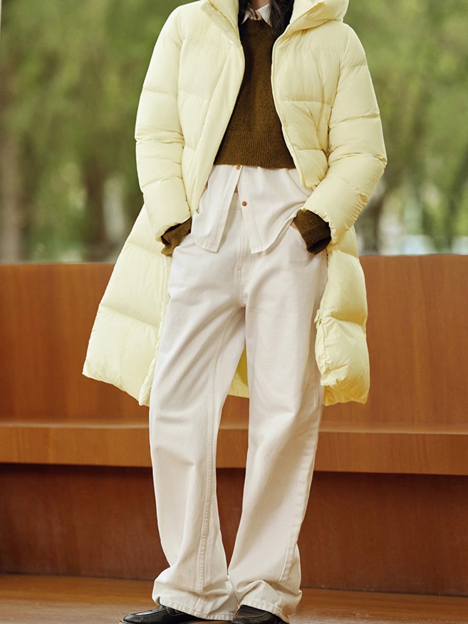 Long puffer coat in Butter worn open with hands in the hidden hip pockets
