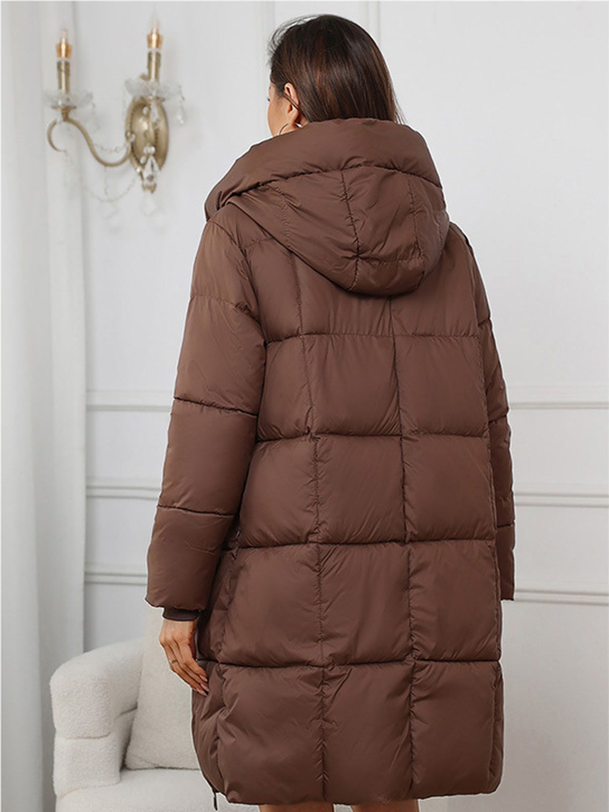 Long puffer coat in Cocoa Brown seen from the back, showing the hood and the quilted panels