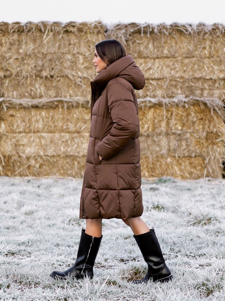 Woman walking in a long brown puffer coat, side view showing the below the knee length