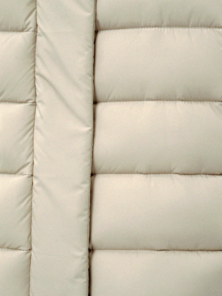 Close up of the wide quilted channels on a long puffer coat in Parchment
