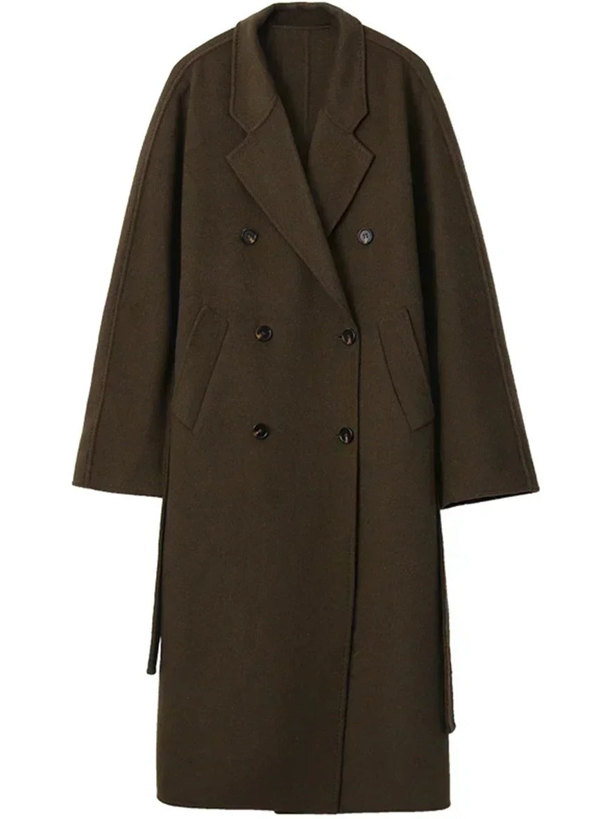 Long wool coat in Treacle on a hanger, showing the double breasted front, the welt pockets and the belt hanging loose