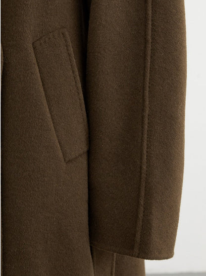 Detail of the slanted welt pocket and the flat topstitched sleeve seam of the double faced wool coat