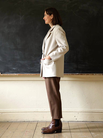 Longline blazer in Plaster cream, side view worn with brown trousers