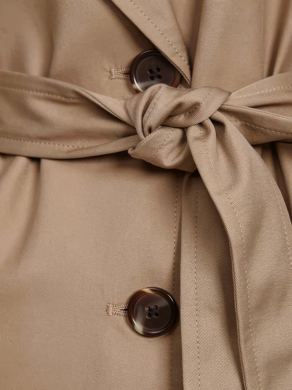 Close up of the matte twill, tie belt and horn buttons on the longline trench coat