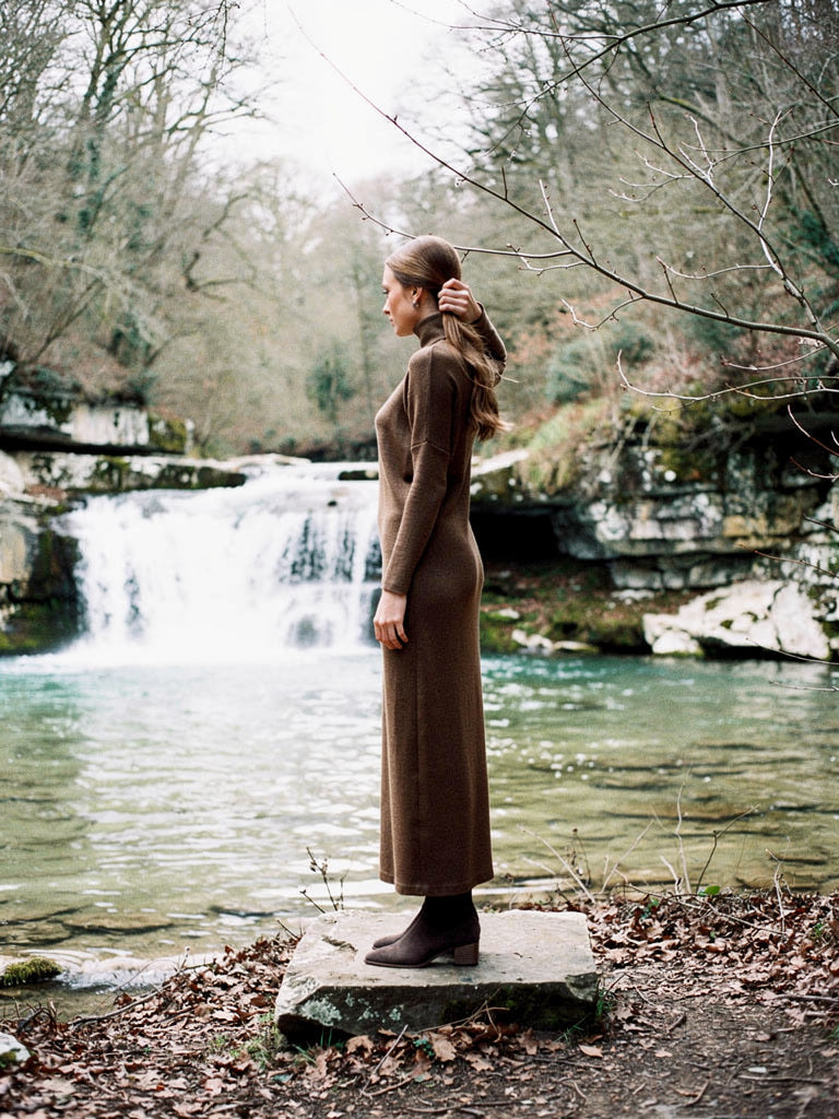 Maxi jumper dress in Hessian worn beside a limestone waterfall, side view, full length